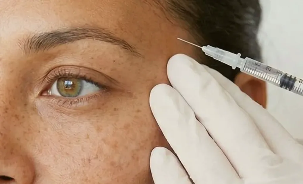 A practitioner administering an injectable treatment beside the eye